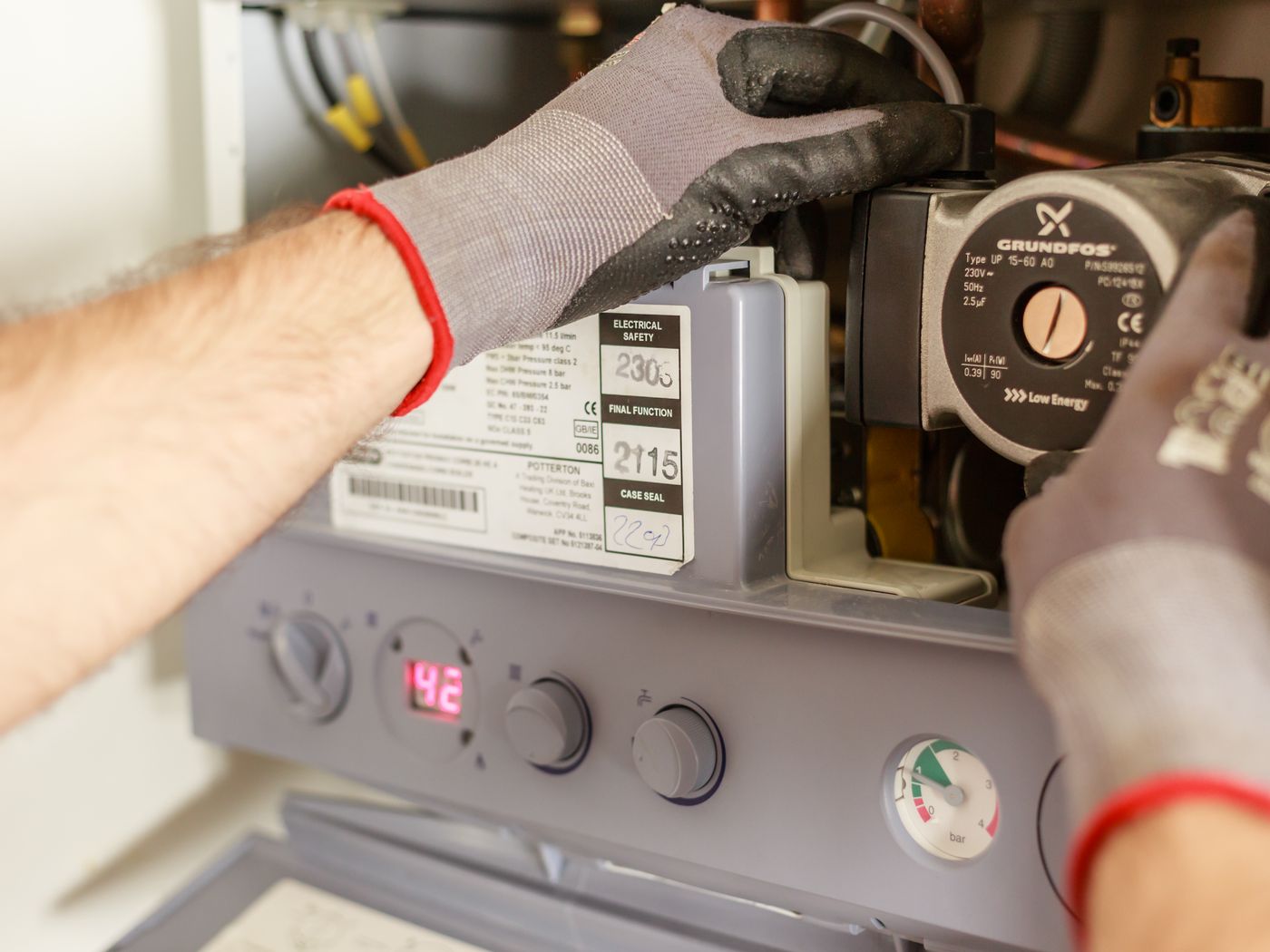 Technician servicing a wall-mounted boiler and circulator pump